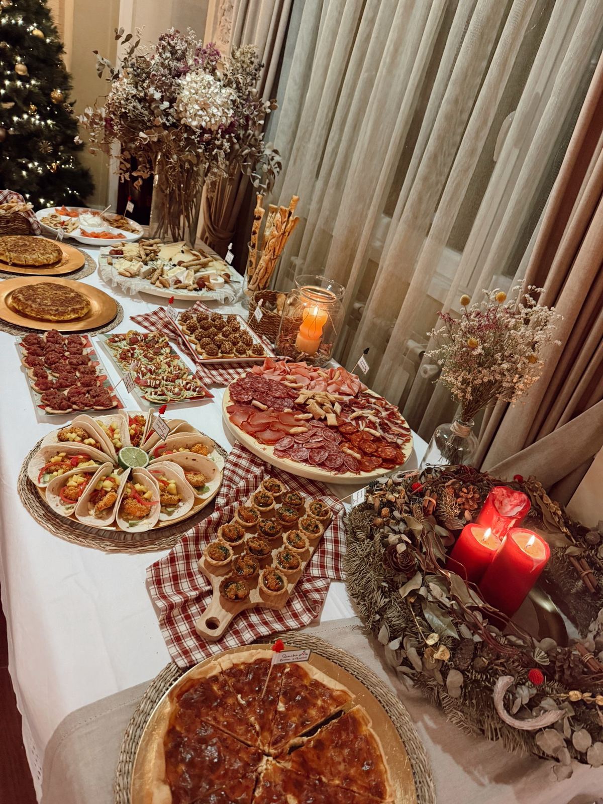 Mesa de cóctel navideña con tortilla, tacos y mini quiches