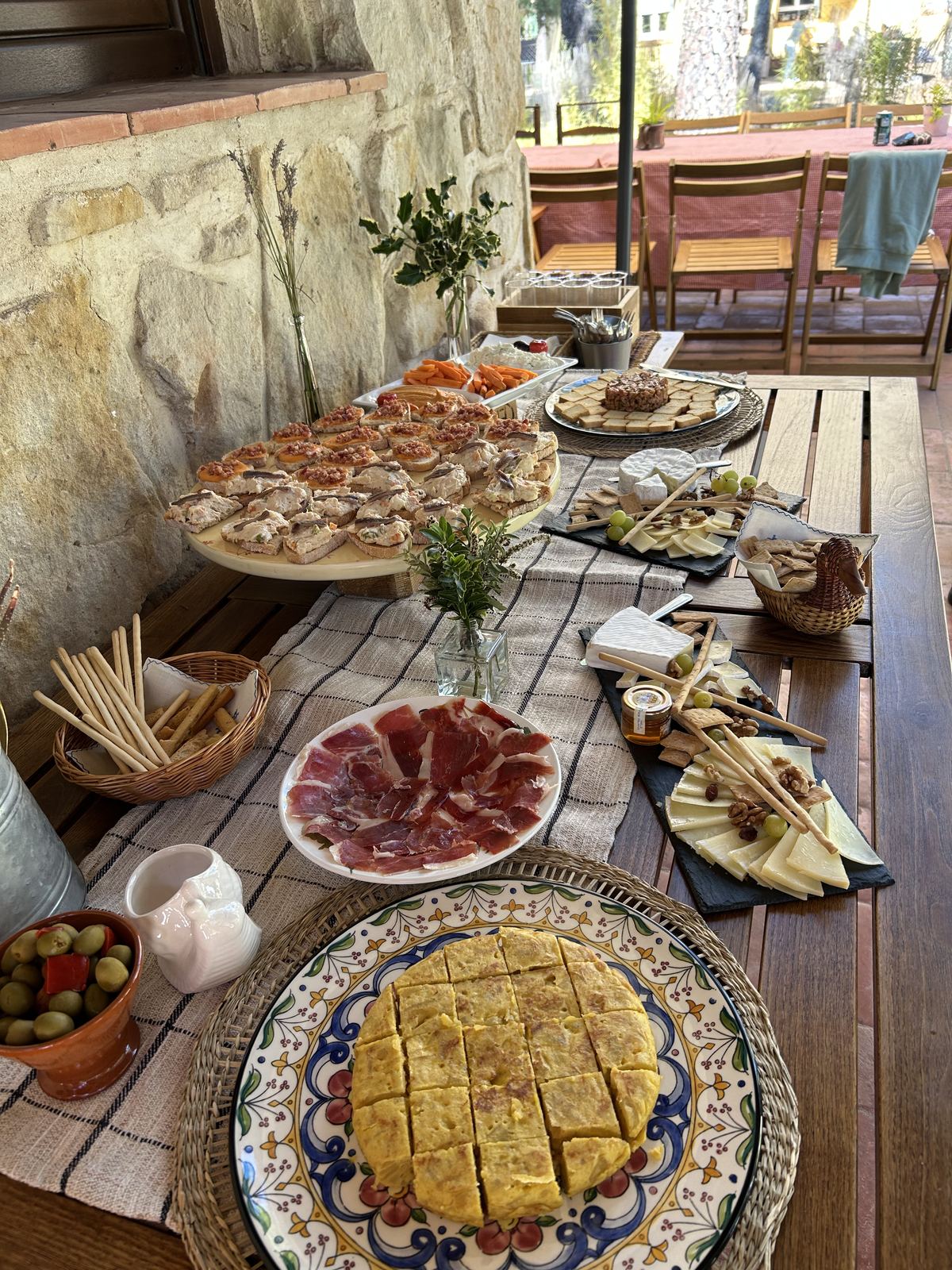 Mesa de cóctel al aire libre con tabla de quesos y jamón